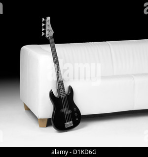 Black bass guitar magra contro lettino bianco in dark indietro Foto Stock