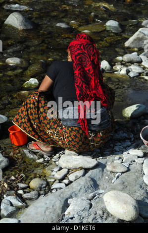 Una donna lava le stoviglie in un flusso in Nepal rurale vicino Phokara, Nepal Foto Stock