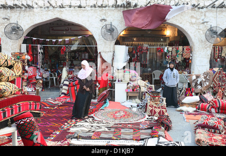 Orazione tessili arabo in vendita in un negozio di Souq Waqif, Doha, Qatar, con negozio di assistenti in attesa di servire i clienti. Foto Stock