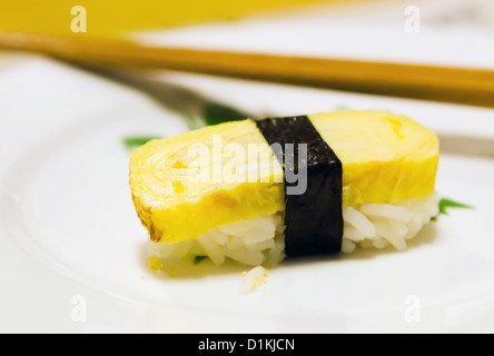 Tamago yaki sushi è utilizzando un uovo su piastra bianca Foto Stock