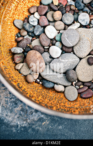 Pietre di fiume in un recipiente rustico. Foto Stock