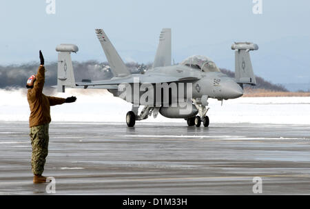 NAVAL AIR FACILITY Misawa combatté, Giappone (dec. n. 28, 2012) di aviazione del macchinista Mate Airman Kenia Palacio, da El Paso, Texas, assegnato ad attacco elettronico Squadron (VAQ) 132's La divisione della linea, segnali per lo spazio racchiuso per l'equipaggio di un EA-16G 'Growler' come i taxi fuori dalla linea di volo a Naval Air Facility Misawa combatté. VAQ-132 è attualmente in sei mesi di distribuzione alla NAF Misawa combatté a sostegno degli Stati Uniti 7 flotta.US Navy foto Foto Stock