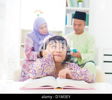 Sud-est asiatico famiglia libro di lettura a casa. Famiglia musulmana stile di vita vivente. Foto Stock