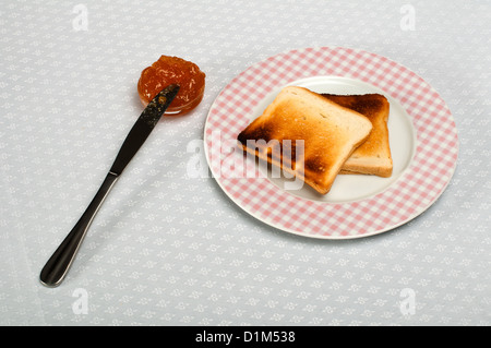 Fetta di pane spalmato con marmellata e coltello su un piccolo recipiente Foto Stock