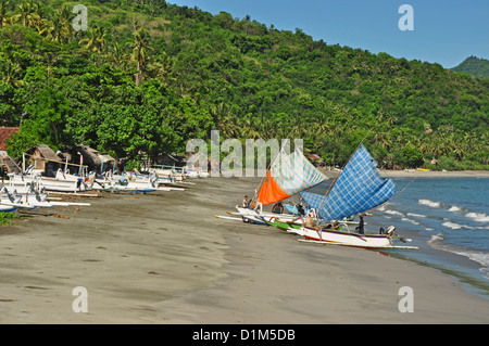 INDONESIA, Bali, Padang Bai, barche da pesca sul litorale con ricca vegetazione dietro Foto Stock