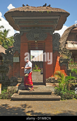 INDONESIA Bali Ubud, tipica casa comunale per ampliare il centro della classe famiglia, ingresso al composto con uomo abito tradizionale Foto Stock