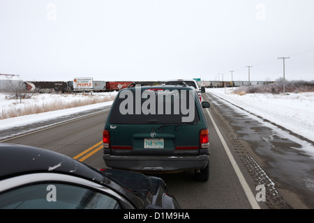 Automobili in attesa sul treno attraversando trans-Canada highway in inverno al di fuori di Yorkton Saskatchewan Canada Foto Stock