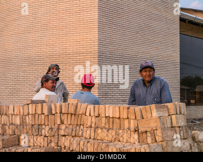 Quattro ispanico lavoratori edili, Indossando cappellini da baseball, sostare davanti a un cantiere in questa città con una forte influenza tedesca. Foto Stock