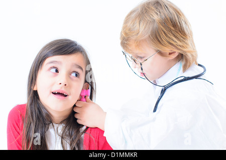 Un ragazzo simpatico attrezzato come un medico la consultazione di una bambina Foto Stock