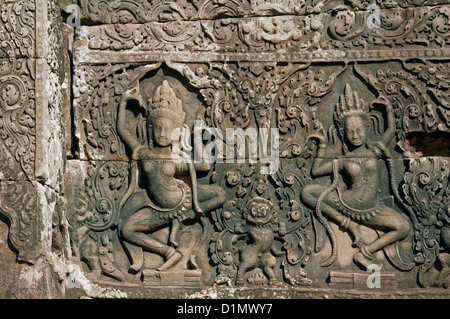 Due danza Apsara incorniciato dalle intricate e foglie intrecciate, modelli di Angkor Thom, Siem Reap, Cambogia Foto Stock