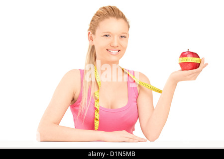 Una femmina sorridente tenendo un apple rosso avvolto con nastro di misurazione isolata su sfondo bianco Foto Stock