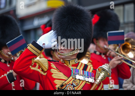 Un membro delle guardie Coldstream ha 'occhi destro' e saluta in Exeter, Regno Unito, 2011. Marching Band membri può essere visto dietro. Foto Stock