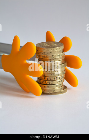 Le mani di raggiungere fuori per pile di £ 1 monete denaro set contro uno sfondo bianco Foto Stock