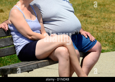 Il sovrappeso obesi uomo si siede con la moglie su un banco di lavoro Foto Stock