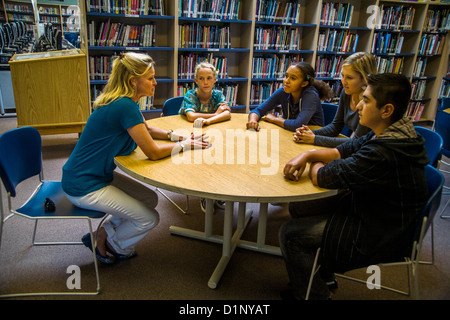 Un junior high school consigliere risponde con un gruppo multietnico di studenti in una San Clemente, CA, biblioteca scolastica. Foto Stock