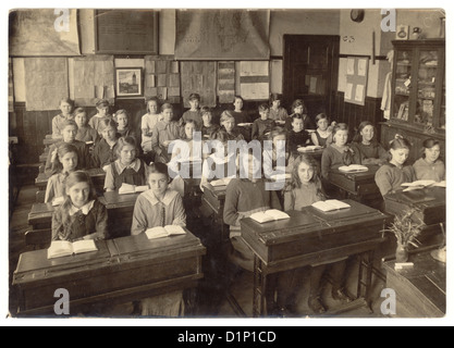 Scuola di fotografia junior ragazze seduti alla scrivania con libri aperti in aula avendo una lezione - 1930, U.K. Foto Stock