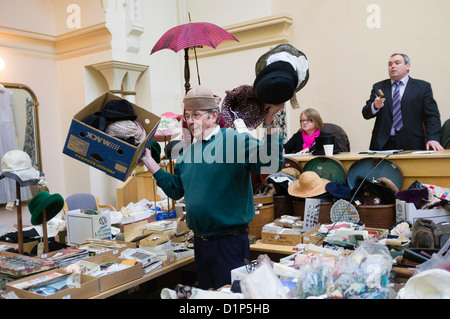 Un assistente che tiene fino cappelli in vendita su un' asta di Antiquariato, abbigliamento e bric-a-brac, REGNO UNITO Foto Stock