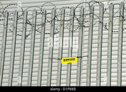 Segnaletica di pericolo attenzione della concertina filo spinato montato su acciaio zincato recinzione appuntita. Foto Stock