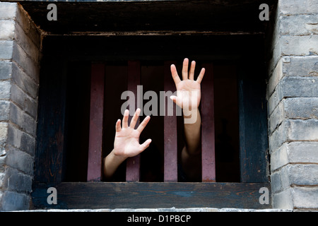 Due mani tratto fuori da cellule in cerca di libertà Foto Stock