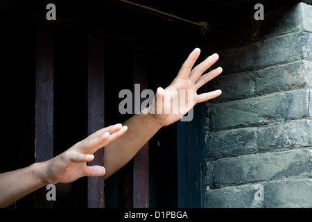 Due mani tratto fuori da cellule in cerca di libertà Foto Stock