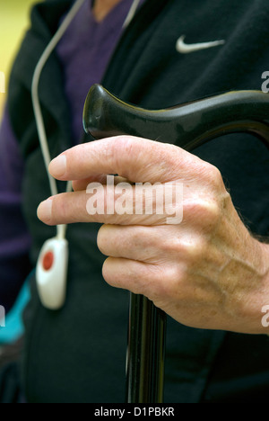 Uomo con disabilità fisica holding bastone & indossando un ciondolo trigger di emergenza Foto Stock