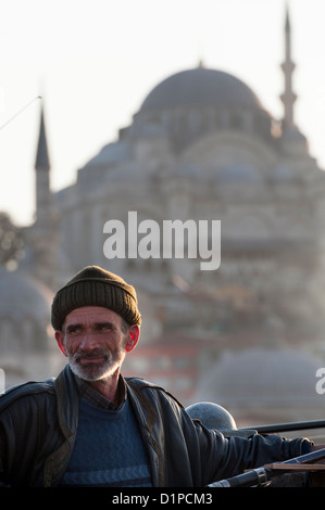 Uomo di pesca con Rustem Pasha moschea in background, Fiume sul Bosforo, Istanbul, Turchia Foto Stock