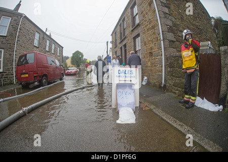 Inondazione in Helston street, servizio antincendio incident commander in carica del controllo di allagamento, Dales macellai aperta come di consueto Foto Stock