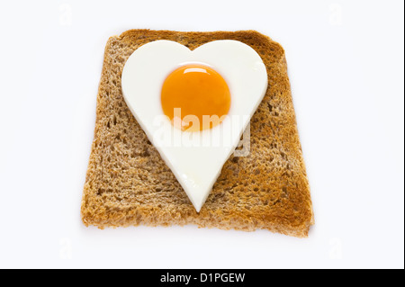 A forma di cuore di uova cotte su una fetta di pane tostato per illustrare l amore di cibo o mangiare sano concetto di colesterolo Foto Stock