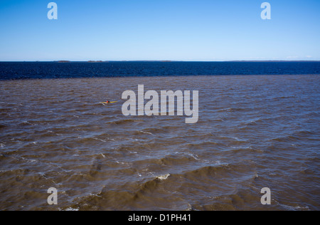 Kayak solitario in mare nel Mar Baltico, acqua poco profonda marrone mescolato con sabbia e blu acqua più profonda, Golfo di Botnia paesaggio, Finlandia Foto Stock