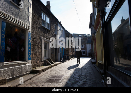 Un uomo cammina attraverso le strette vie del Cornish Harbour Town St Ives Foto Stock