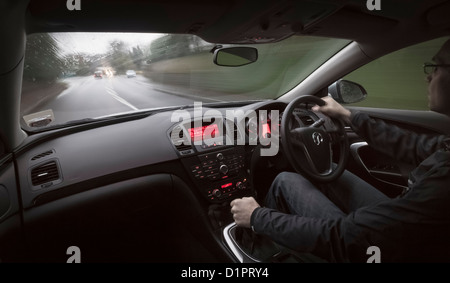 Guida lungo una strada bagnata al crepuscolo dall'interno dell'auto. Foto Stock