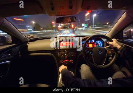 La guida veloce verso una vettura ferma in corrispondenza di luci di notte dall'interno dell'auto. Foto Stock