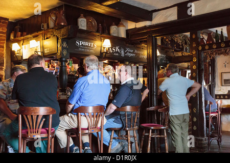 Gli uomini seduti su sedie in corrispondenza di un bar interno haunted xv secolo Old Black Horse pub con travi di legno in Pluckley, Kent, England, Regno Unito Foto Stock