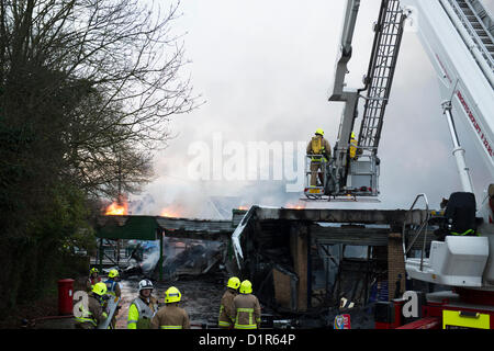 Laindon, Basildon, Essex. Quattro negozi sono stati rasi al suolo dopo un incendio appiccato in un cinese take-away in parata noto come il Triangolo negozi. Si ritiene che l incendio è scoppiato in un aeratore e diffondersi a tutta la sfilata di distruggere altre tre imprese. Gli altri negozi erano un parrucchiere, un ufficio postale e un negozio di generi alimentari. Non è noto per aver causato danni. Due vigili del fuoco su di una piattaforma aerea pronti a combattere il fuoco da sopra. Foto Stock