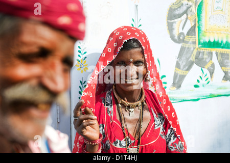 Un colorato ritratto di Rajasthani l uomo e la donna in costume tradizionale in piedi di fronte ad una parete decorativa con un elefante Foto Stock