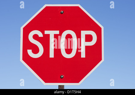 Il segnale di arresto sul montante metallico con cielo blu sullo sfondo Foto Stock