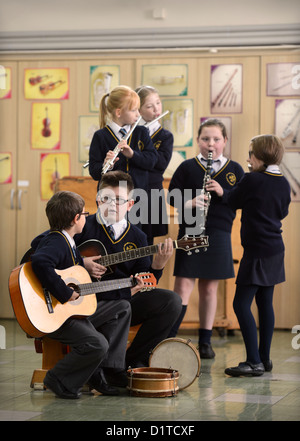 Ragazzi pratica sul loro chitarre durante una lezione di musica la Madonna e San Werburgh Cattolico della scuola primaria a Newcastle-under-Lyme, Foto Stock