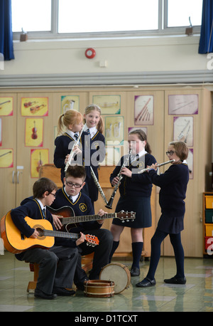 Ragazzi pratica sul loro chitarre durante una lezione di musica la Madonna e San Werburgh Cattolico della scuola primaria a Newcastle-under-Lyme, Foto Stock