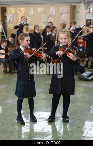 Due ragazze la riproduzione di violini a una lezione di musica la Madonna e San Werburgh Cattolico della scuola primaria a Newcastle-under-Lyme, Staffords Foto Stock