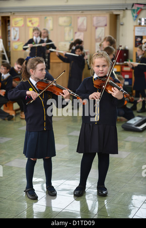 Due ragazze la riproduzione di violini a una lezione di musica la Madonna e San Werburgh Cattolico della scuola primaria a Newcastle-under-Lyme, Staffords Foto Stock