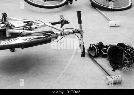 Una immagine in bianco e nero di una bicicletta che stabilisce sulla corte  di cemento con il casco e un mazzuolo in tra bike polo giochi in un tourny  Foto stock -