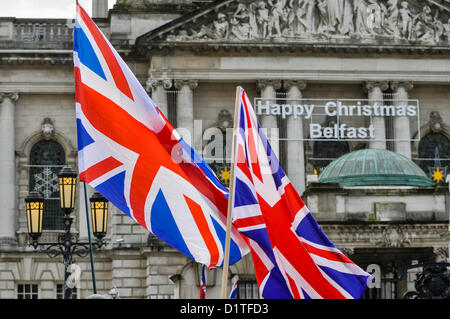 Dal 5 gennaio 2013. Belfast, Irlanda del Nord - Due bandiere Unione volare nella parte anteriore del Belfast City Hall, che ha 'Felice Natale Belfast' segno come parte delle decorazioni. Foto Stock