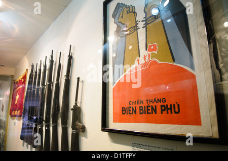 Dien Bien Phu Victory Propaganda poster fucili Rivoluzione Vietnamita Museo Hanoi Vietnam | HANOI, Vietnam — Un poster del 1984 intitolato "Chien Thang Dien Bien Phu" è appeso accanto a una cremagliera di fucili d'epoca all'interno del Museo della Rivoluzione vietnamita, commemorando la cattura del bunker di comando francese da parte dei Viet Minh il 7 maggio 1954. L'assedio di 56 giorni di Dien Bien Phu ruppe il potere coloniale francese in Indocina e portò direttamente agli accordi di Ginevra del 1954. Foto Stock