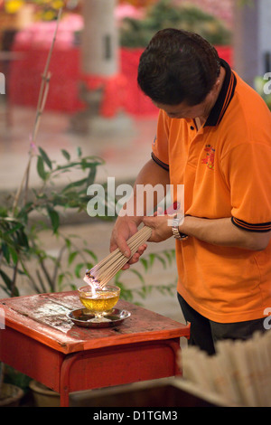 Un Buddista devoto luoghi offerte di incenso presso un santuario in Chinese Thean Hou tempio di Penang, Malaysia Foto Stock