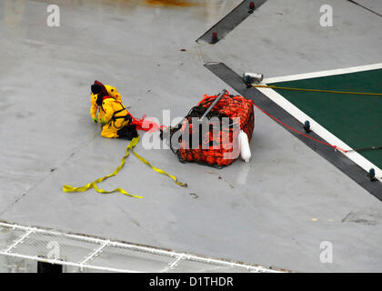 Una squadra di soccorso a bordo di Royal Dutch Shell conica dell'unità di foratura Kulluk avvolge le linee da una il traino in caso di emergenza il sistema ha erogato da un U.S. Coast Guard MH-60T elicottero Jayhawk gen. 5, 2013., 40 miglia a sud-ovest della città di Kodiak, Alaska, sulla riva di Sitkalidak isola. (U.S. Coast Guard foto di Sottufficiali di prima classe e Travis Marsh/rilasciato) Foto Stock