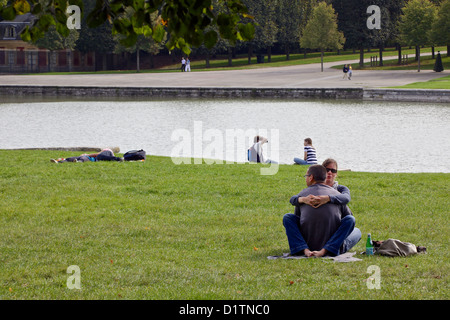 Una coppia giovane e sit abbracciarsi nei giardini del Palazzo di Versailles, Parigi, Francia Foto Stock
