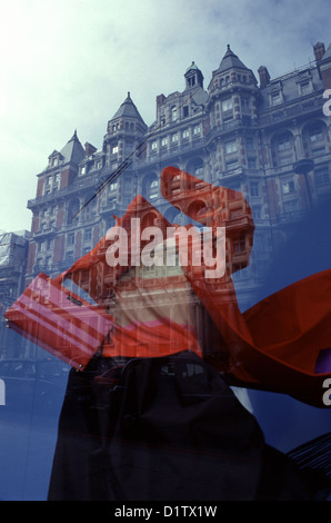 Riflesso dell'edificio in stile edoardiano del Mandarin Oriental Hyde Park in una vetrina che mostra un manichino vestito con un audace e vibrante abito rosso situato nell'area di Knightsbridge nella città di Londra nel Regno Unito Foto Stock
