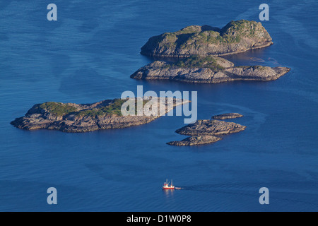 Una prospettiva aerea di pesca in barca a vela tra dalle isolette rocciose vicino Henningsvaer sulle isole Lofoten in Norvegia Foto Stock