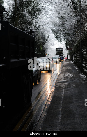 Rush Hour di accodamento del traffico su un gelido inverno nevoso road con le auto con i fari accesi sulla a41 in tettenhall, Wolverhampton, England Regno Unito Foto Stock