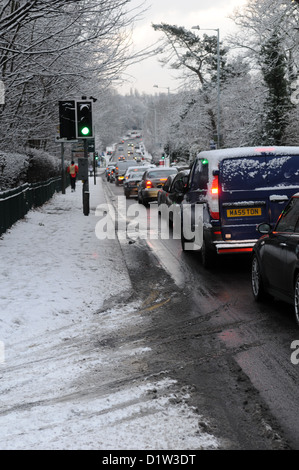 Rush Hour di accodamento del traffico su un gelido inverno nevoso road con le auto con i fari accesi sulla a41 in tettenhall, Wolverhampton, England Regno Unito Foto Stock